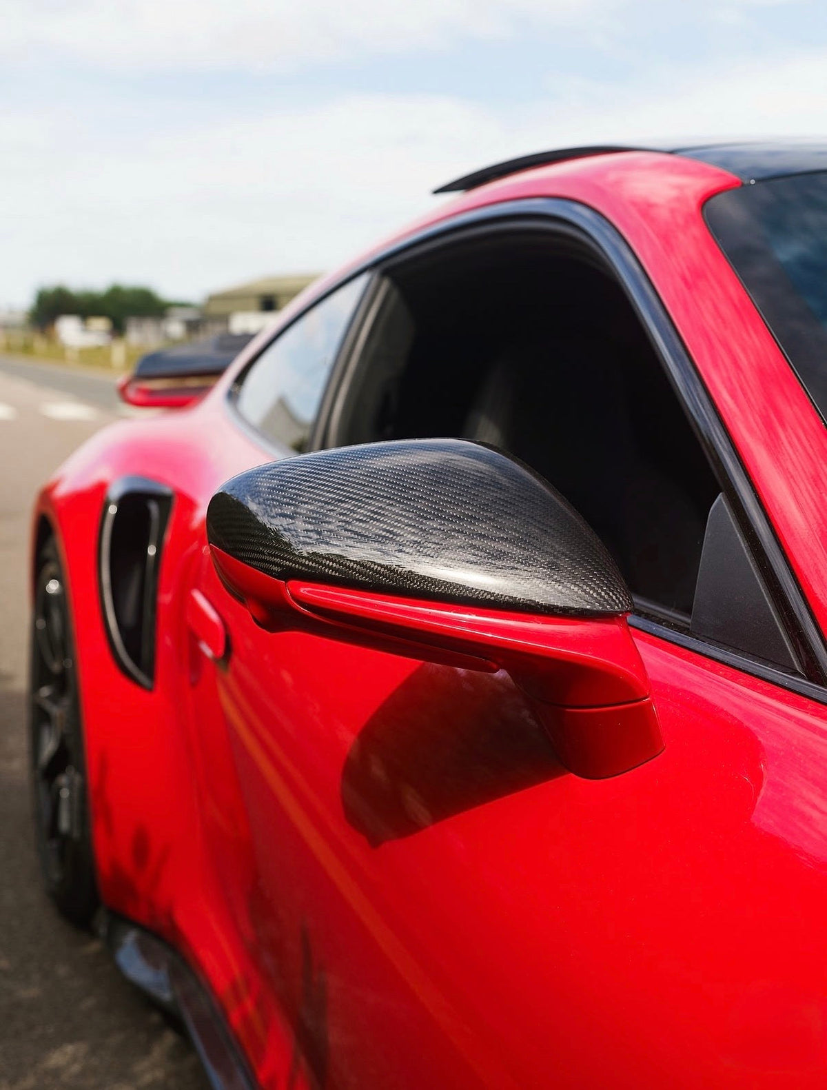 CPG + Dry-Carbon Spiegelkappe an einem roten Porsche 911 992 – seitliche Nahaufnahme mit sportlicher Carbonoptik