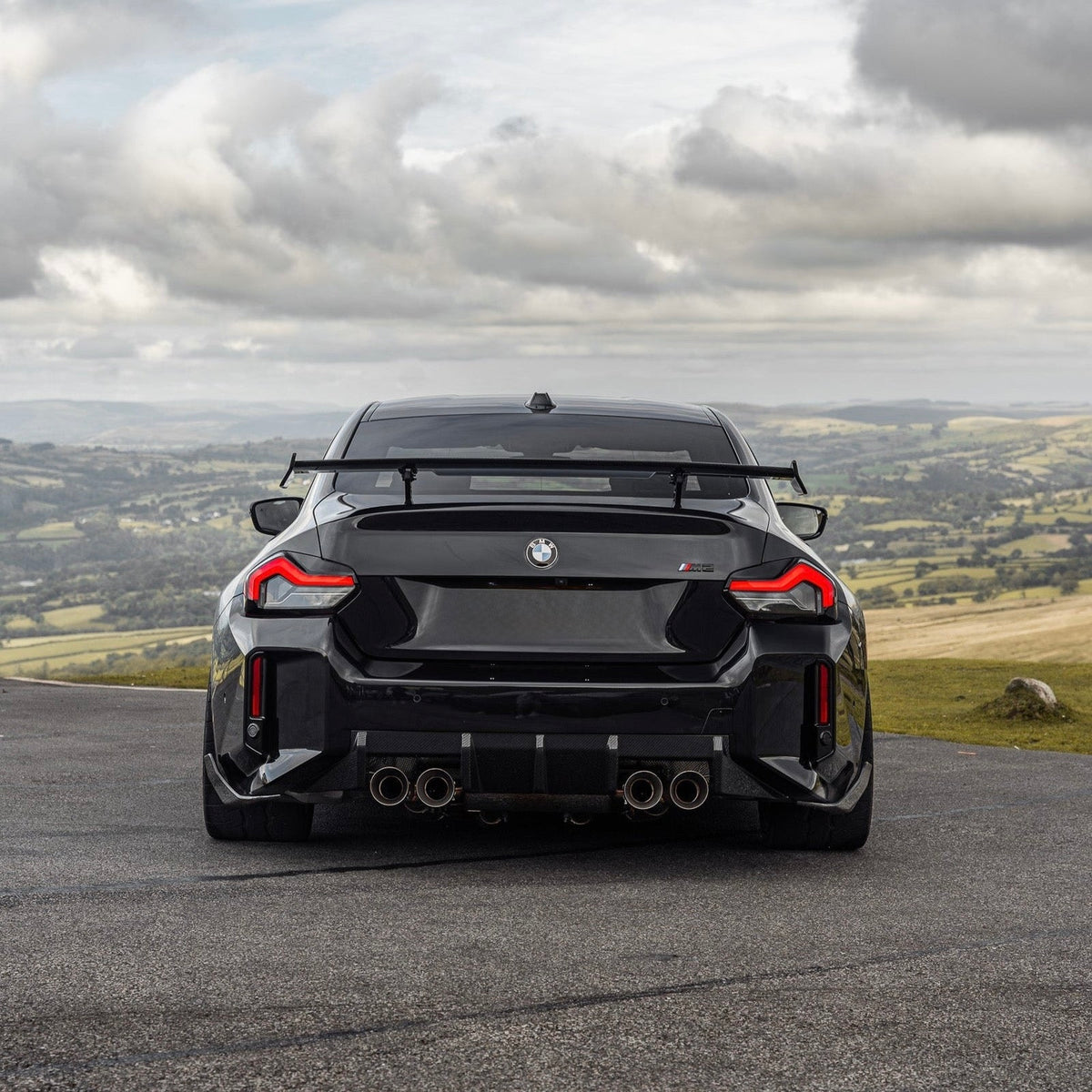 BMW M2 G87 mit Carbon Heckdiffuser V3 – Heckansicht vor Landschaft