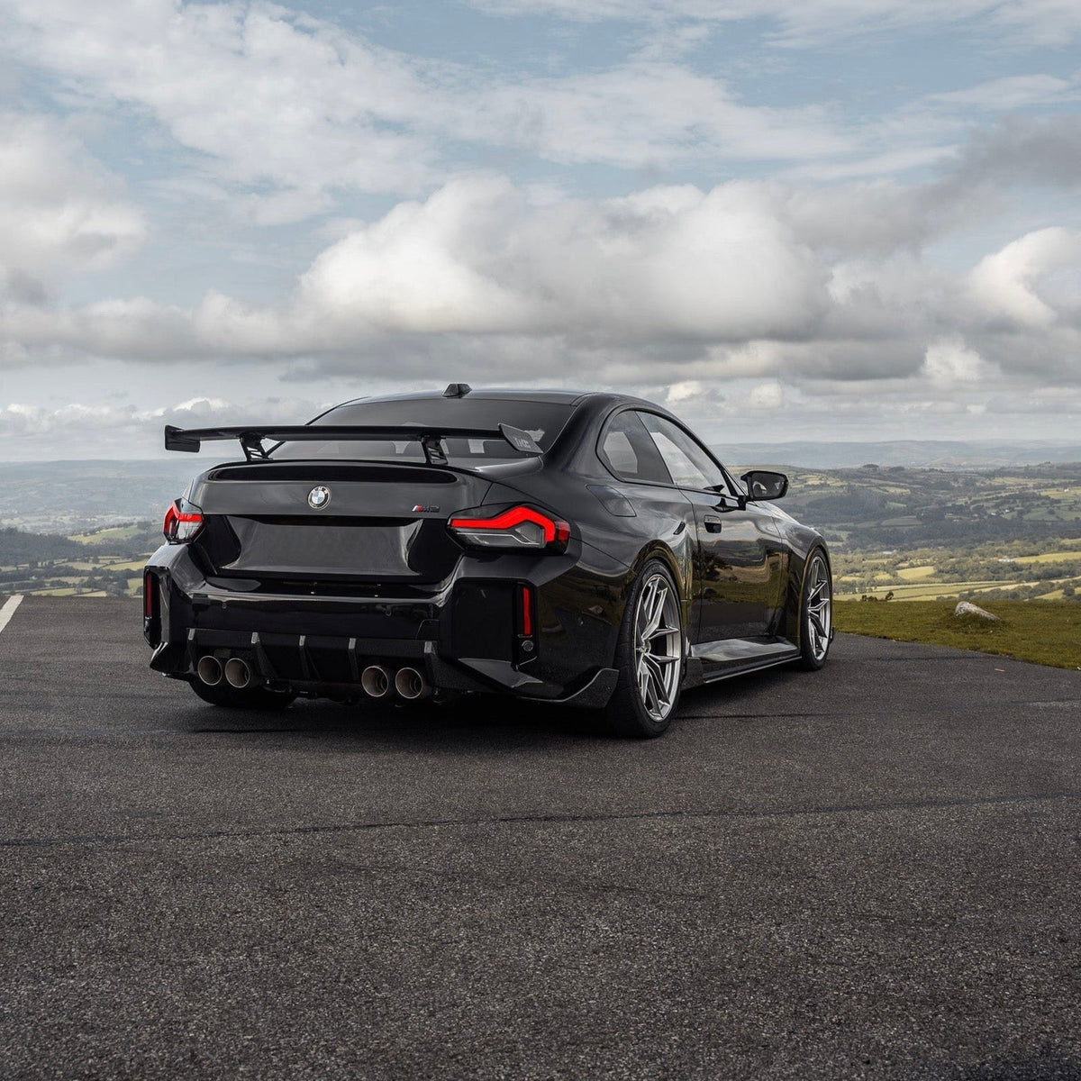 Schwarzer BMW M2 G87 mit V3 Carbon Heckdiffuser – schräge Heckansicht im Freien