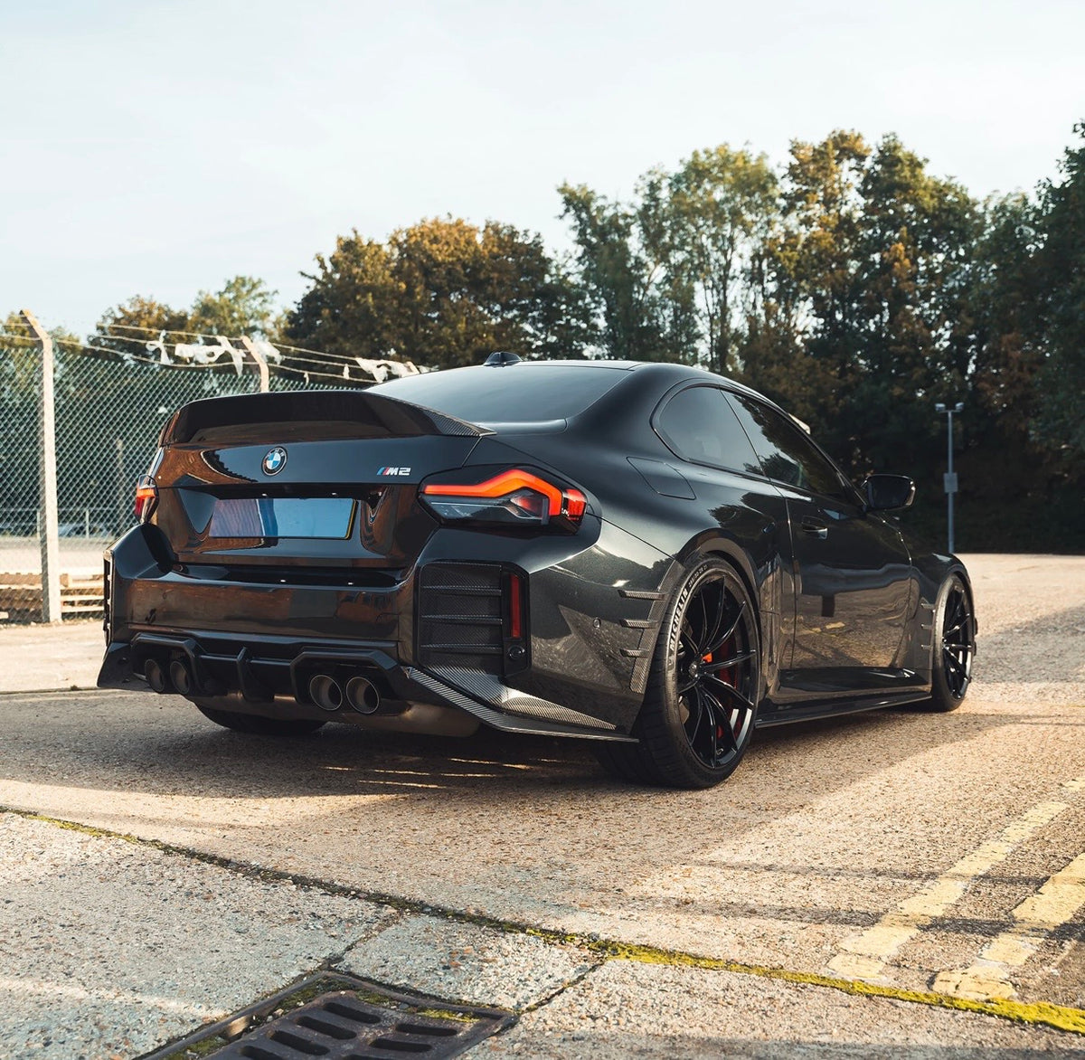 BMW M2 G87 in dunkler Lackierung mit CPG + V7 Carbon Heckdiffuser – schräge Heckansicht im Freien