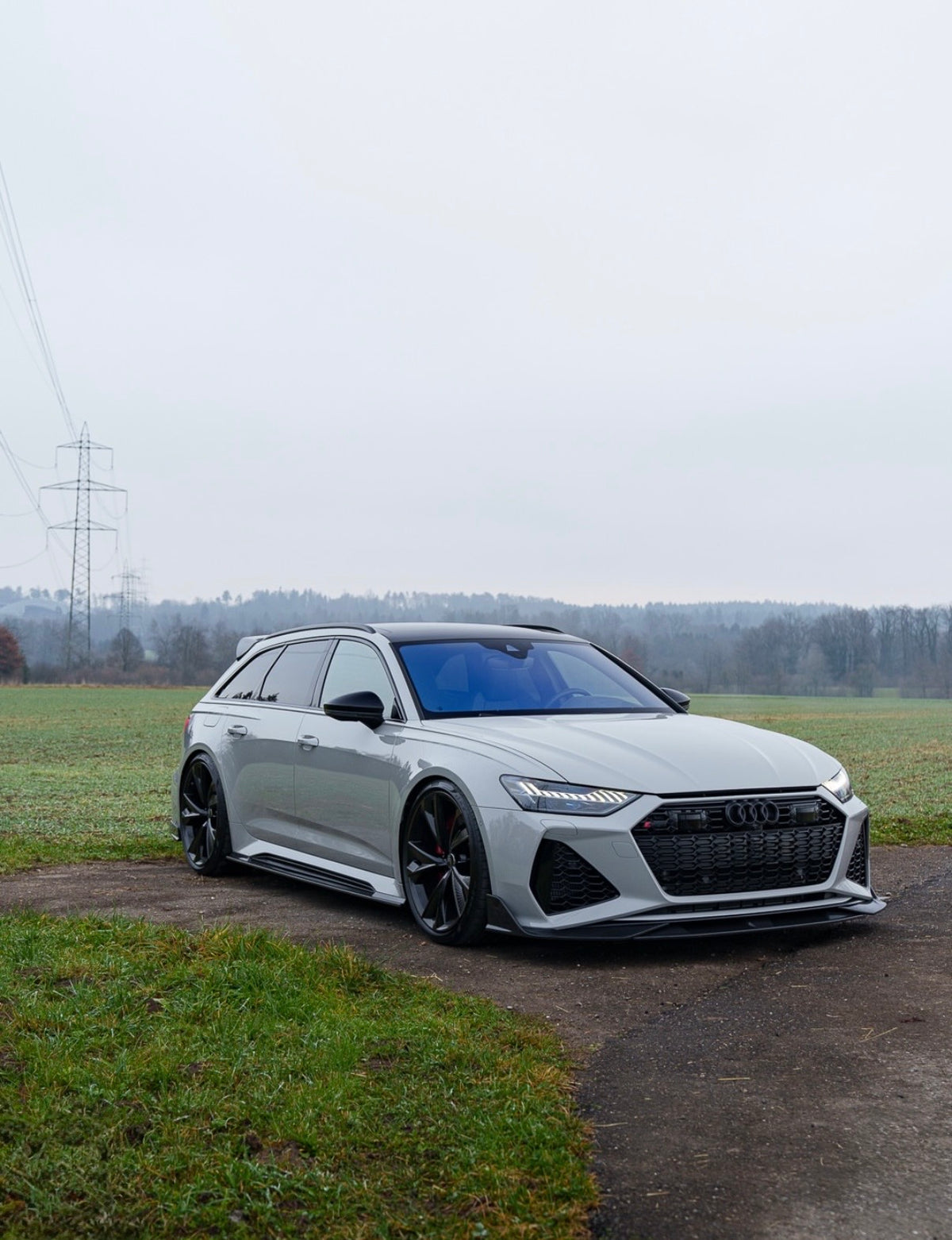 Weißer Audi RS6 C8 Avant mit CPG + V1 Carbon Seitenschwellern in der Front-Seitenansicht