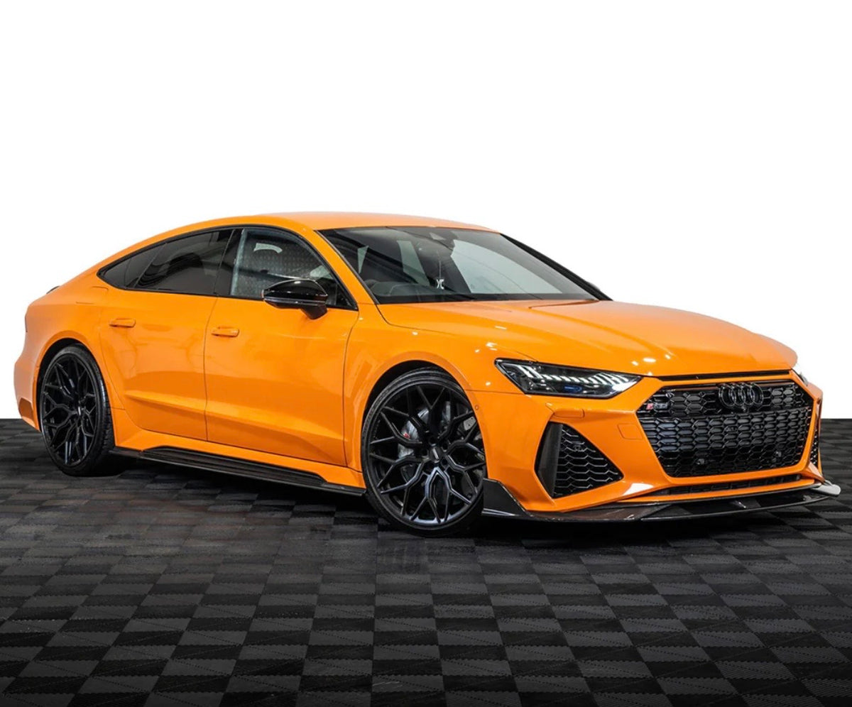 Orangefarbener Audi RS7 Sportback C8 mit V1 Carbon Aerodynamikpaket – schräge Frontansicht