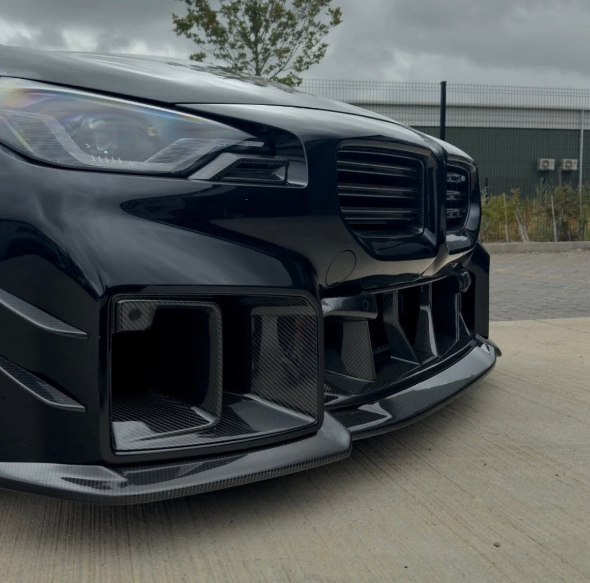 BMW M2 G87 mit CPG + V4 Frontstoßstangeneinsatz aus Dry-Carbon in sportlicher Frontansicht.
