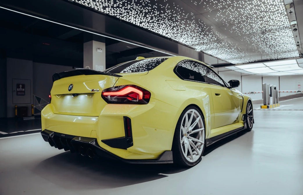 Gelber BMW M2 G87 mit sportlicher Heckansicht und Carbon-Aerodynamikdetails