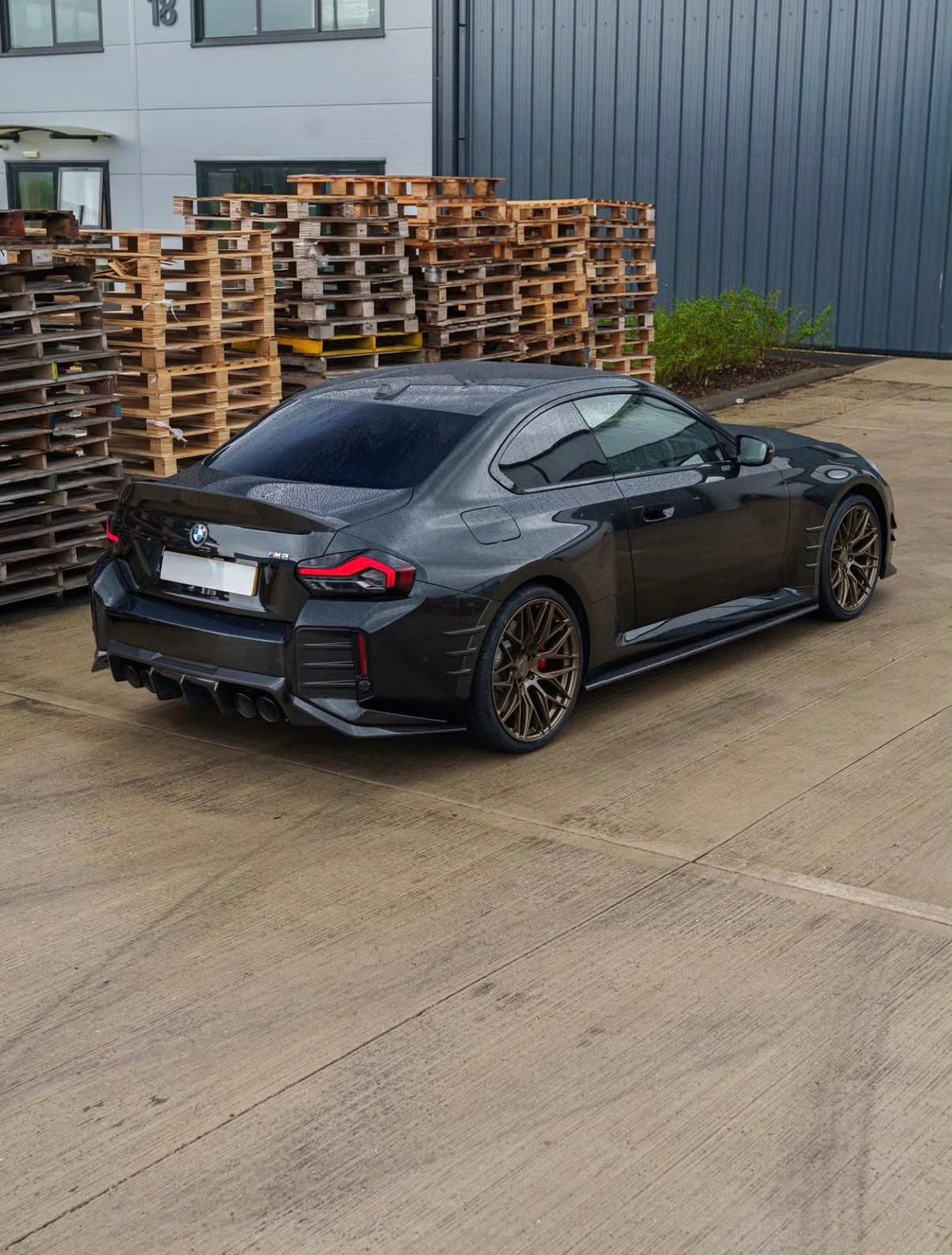Schwarzer BMW M2 G87 mit V2 Carbon Heckstoßstangeneinsätzen in der Heckansicht