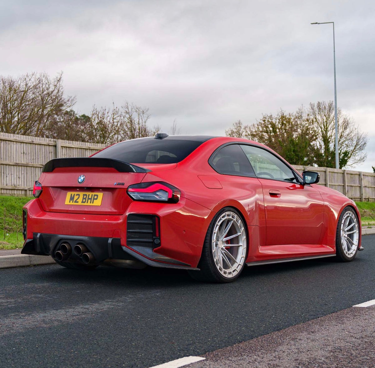 BMW M2 G87 in Rot mit sportlichen V2 Carbon Einsätzen an der Heckstoßstange