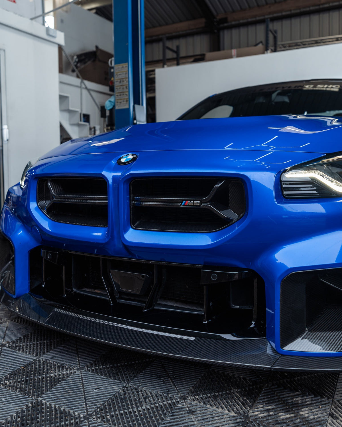 Montierter CPG + V2 Carbon Frontgrill an einem blauen BMW M2 G87 mit sportlicher Frontstoßstange.