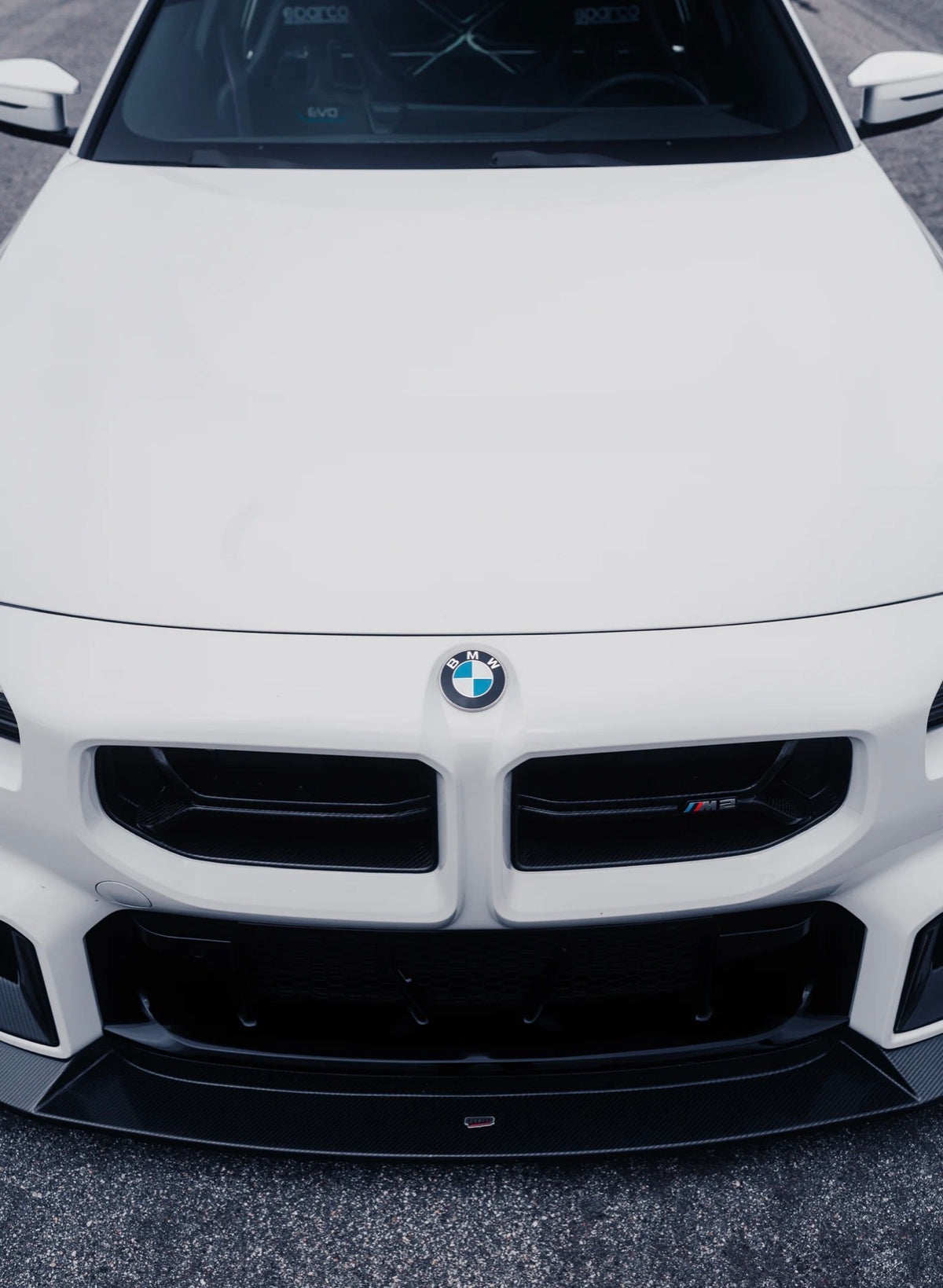 BMW M2 G87 in Weiß mit CPG + V2 Frontgrill aus Dry-Carbon in der Gesamtansicht von vorne.