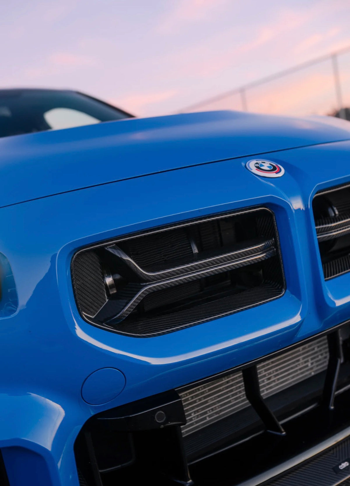 Detailaufnahme des CPG + V2 Dry-Carbon Kühlergrills am blauen BMW M2 G87.