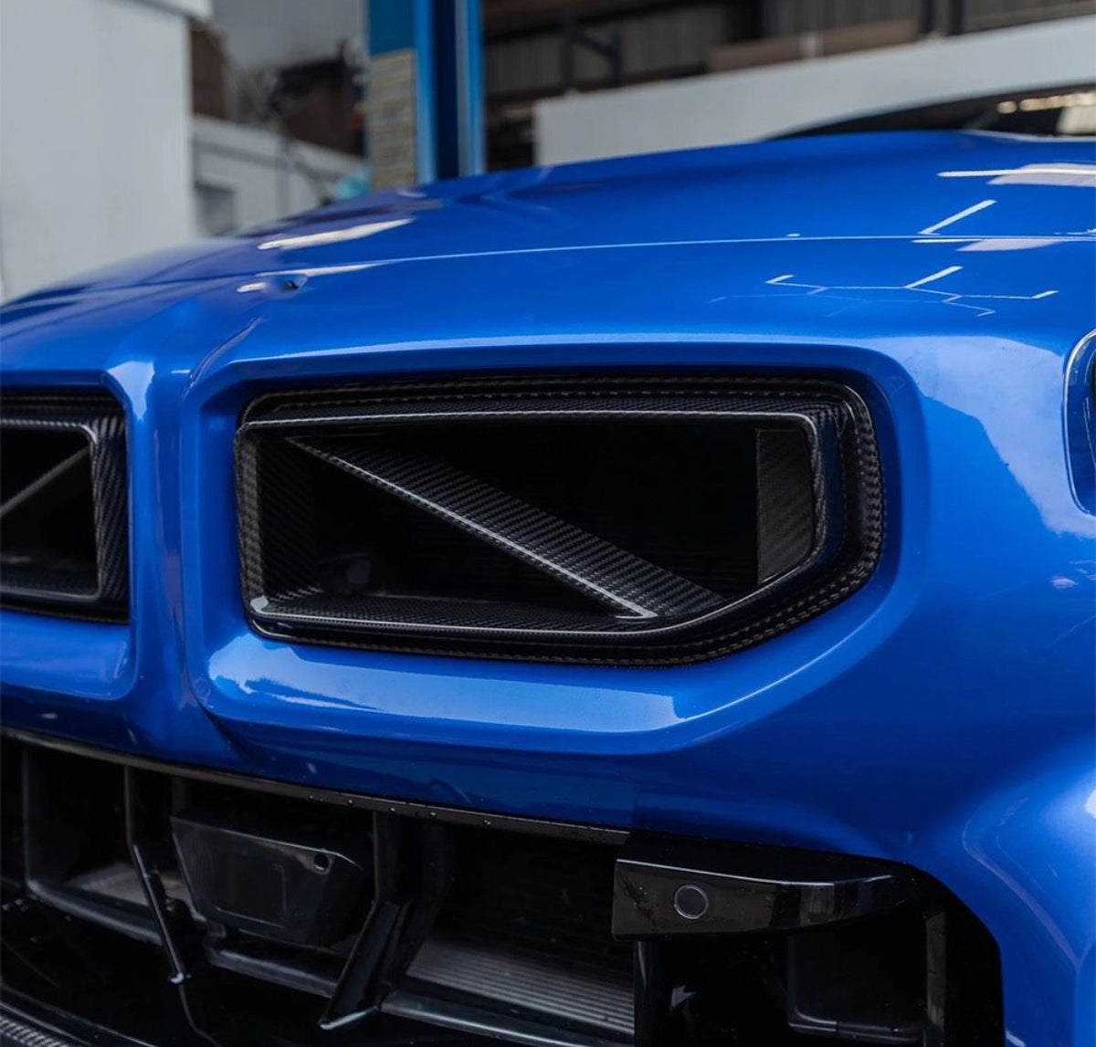 Detailaufnahme des V3 Dry-Carbon Kühlergrills mit markanten diagonalen Streben am BMW M2 G87.