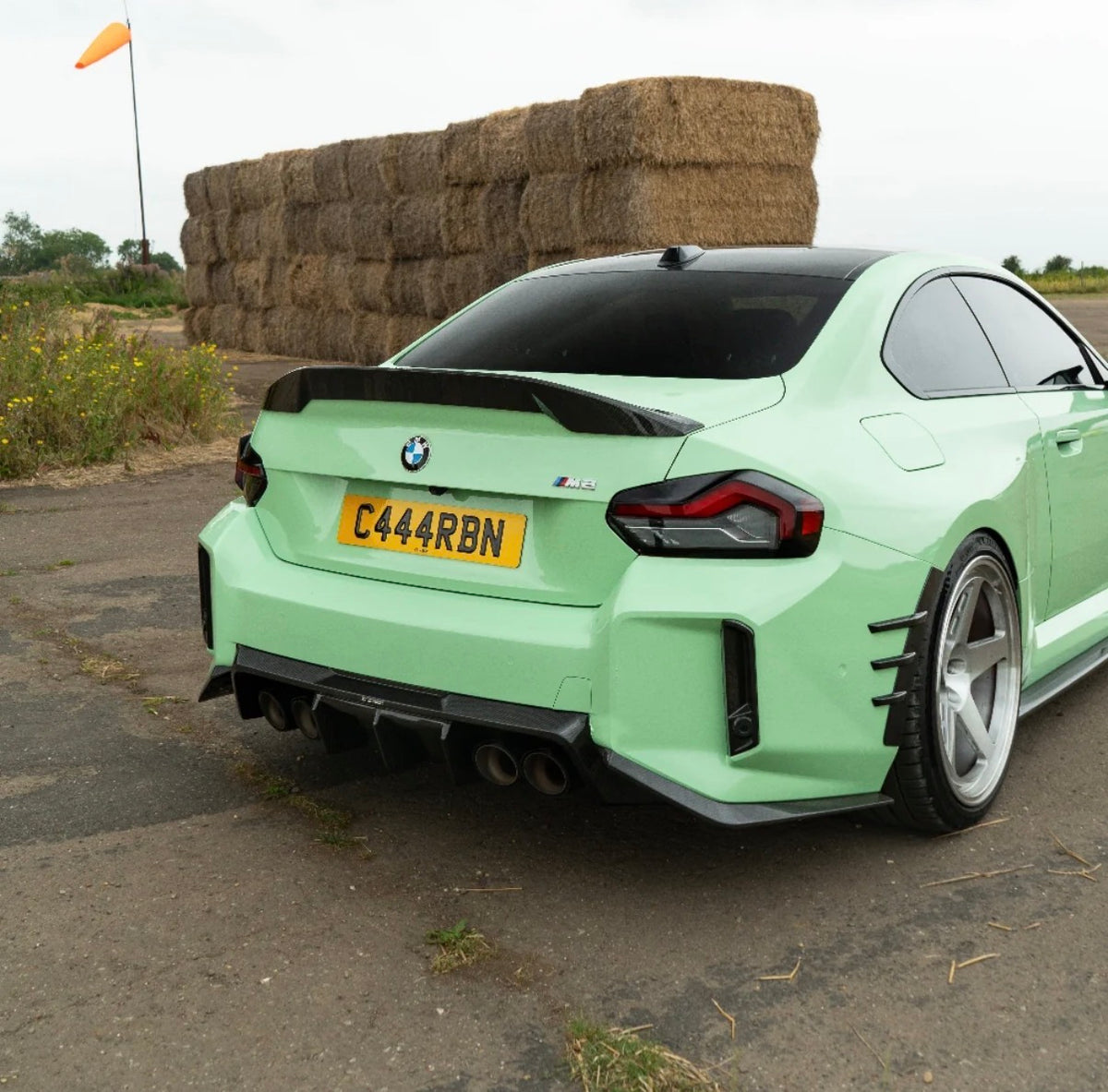 Detailansicht des V4 Carbon Heckspoilers am grünen BMW M2 G87 mit geschwungener Spoilerkontur