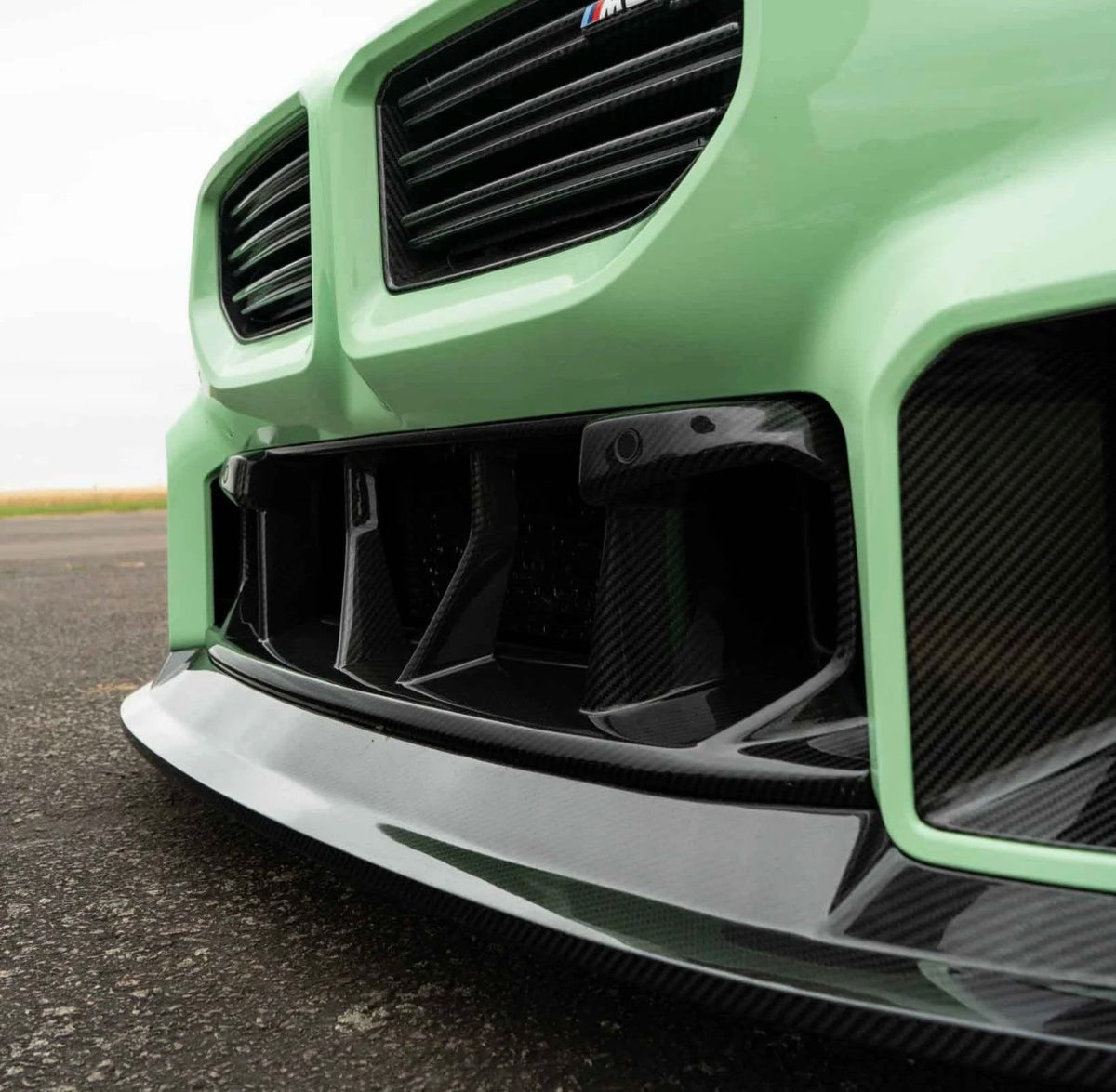 Grüner BMW M2 G87 mit CPG + V4 Carbon Frontstoßstangeneinsatz als hochwertiges Replacement-Bauteil.
