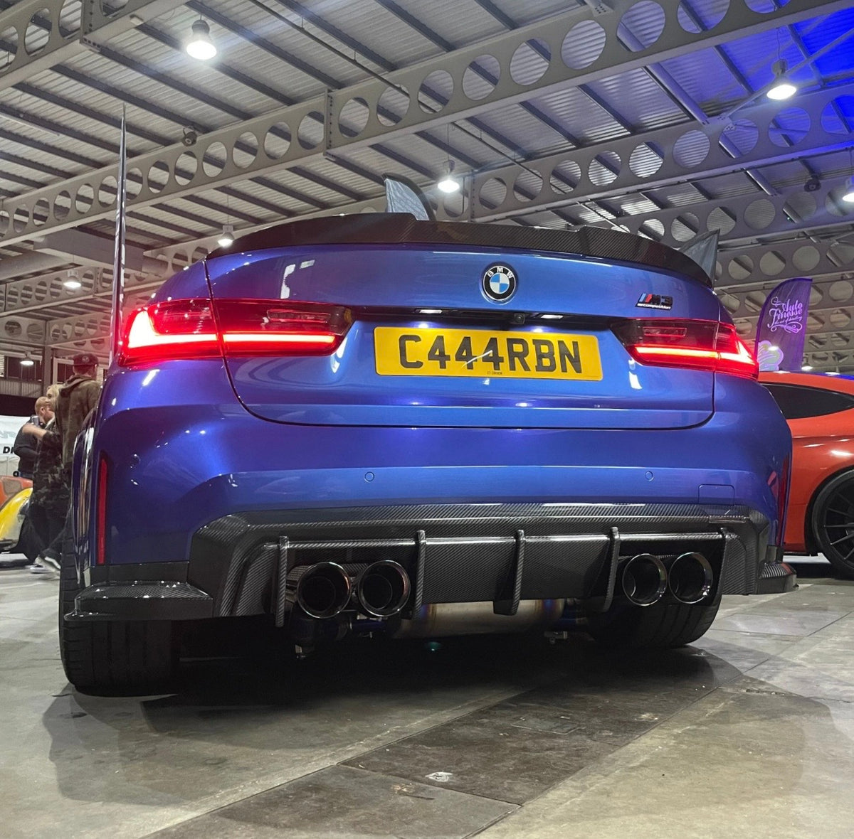 Blauer BMW M3 G80 mit CPG+ V3 Dry-Carbon Heckdiffuser und Sideblades – Heckansicht in einer Fahrzeughalle