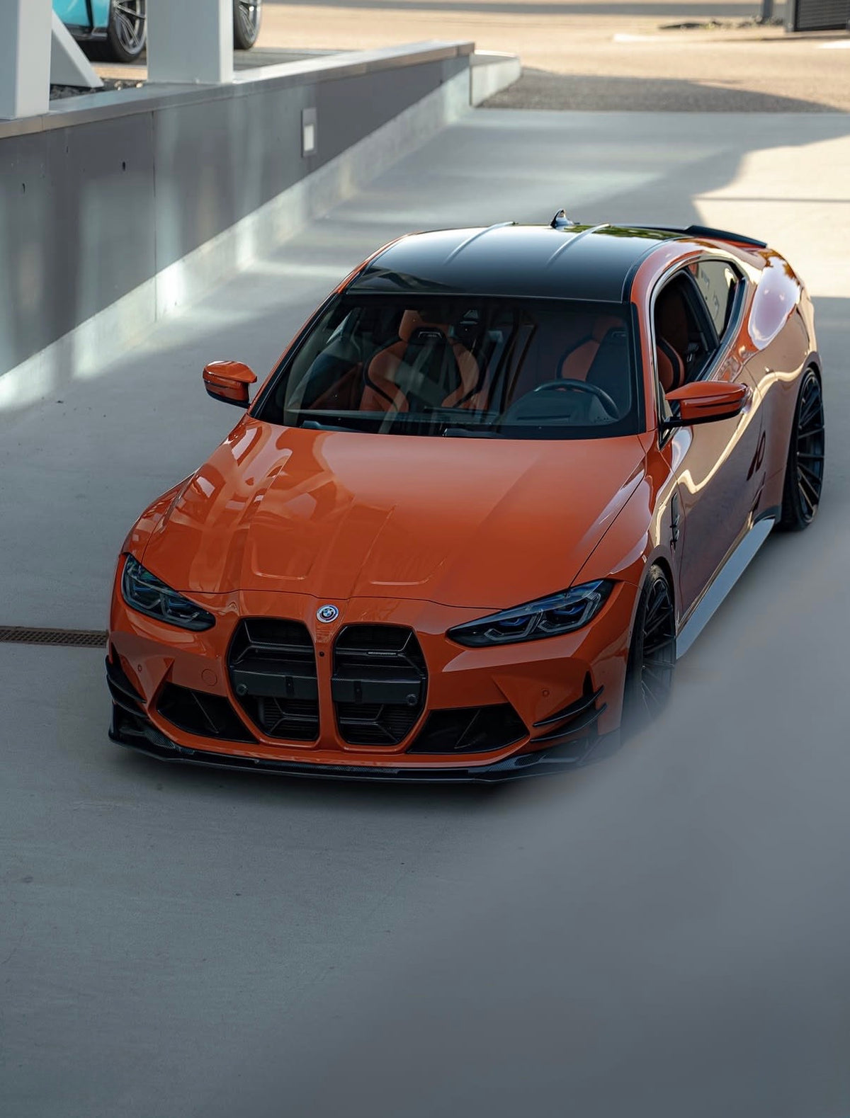 Orangefarbener BMW M3 G80 mit montierter CPG+ V6 Carbon Frontlippe – Detailansicht der Fahrzeugfront