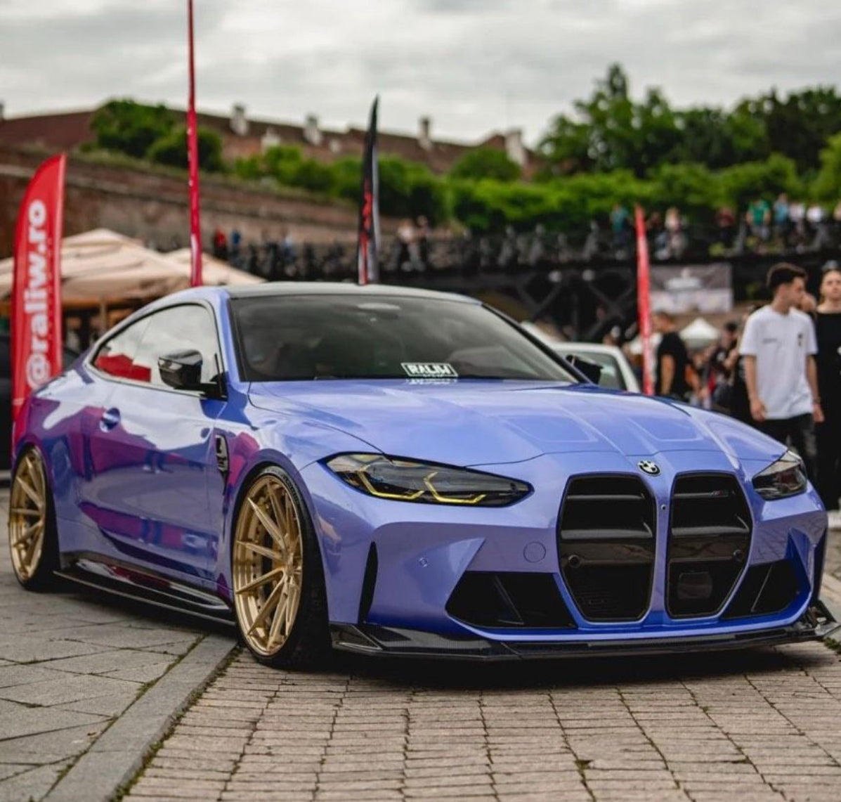 Blauer BMW M3 G80 mit CPG+ V6 Carbon Frontspoiler bei einer Fahrzeugausstellung