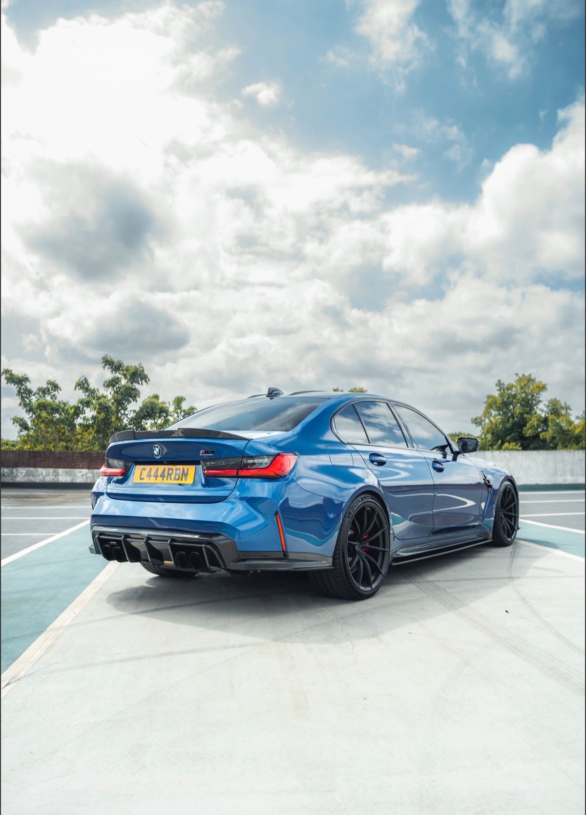 Blauer BMW M3 G80 mit V6 Carbon Seitenschwellern und sportlichem Carbon Body Kit in schräger Heckansicht