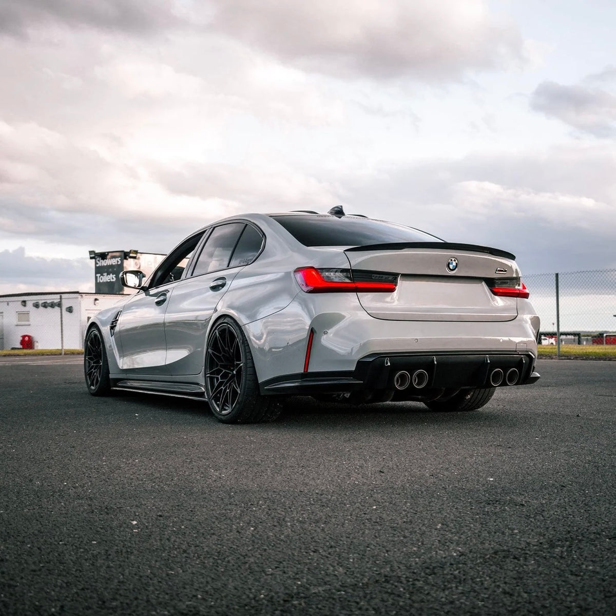 Weißer BMW M3 G80 mit sportlichem V6 Carbon Heckspoiler aus der Heckperspektive