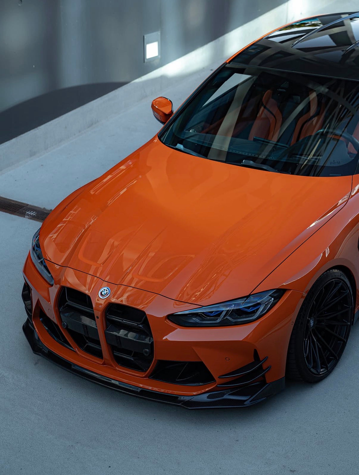 BMW M3 G80 in Orange mit einteiliger CPG+ V6 Dry-Carbon Frontlippe in der Vorderansicht