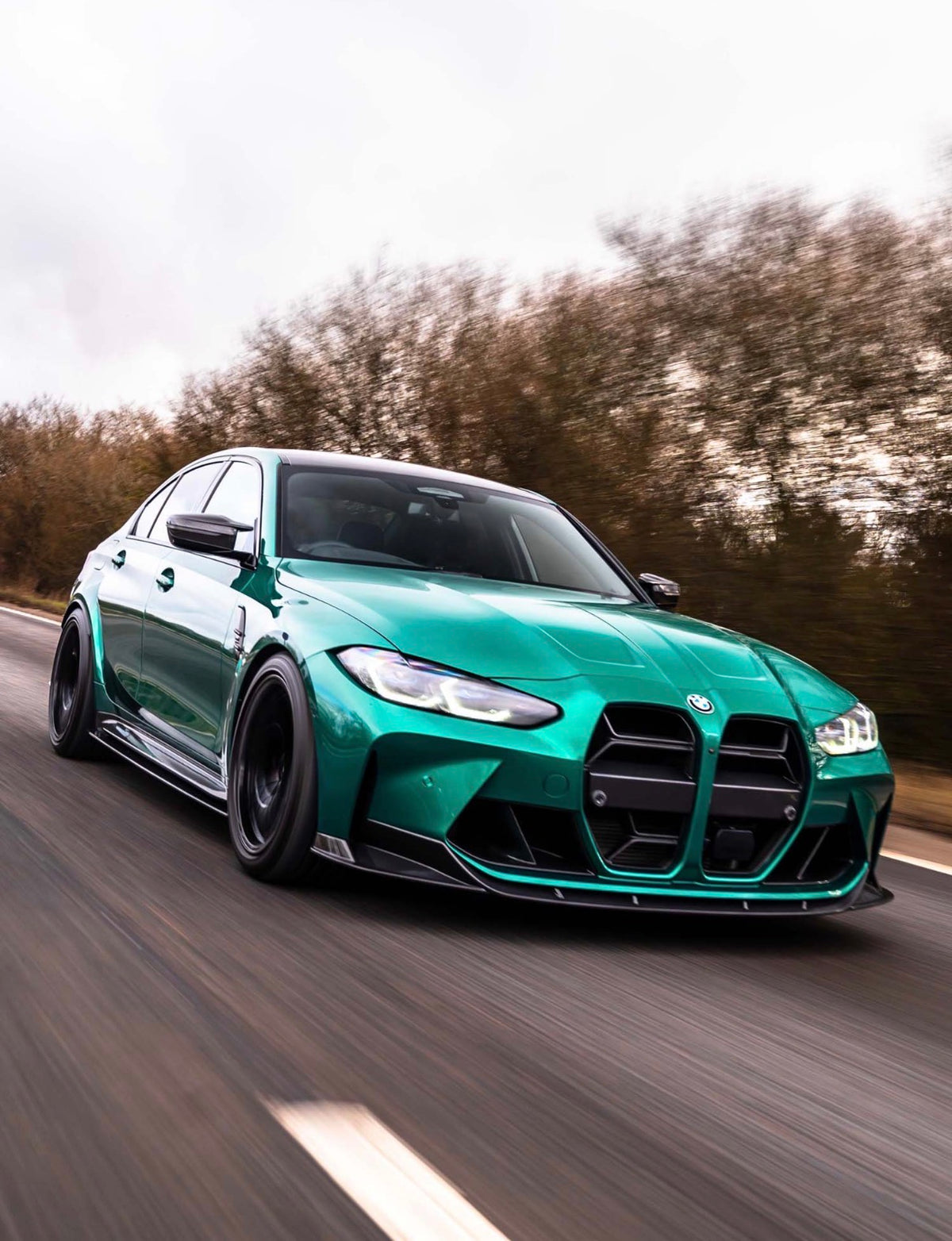 Grüner BMW M3 G80 mit CPG+ V6 Dry-Carbon Seitenschwellern in dynamischer Frontansicht