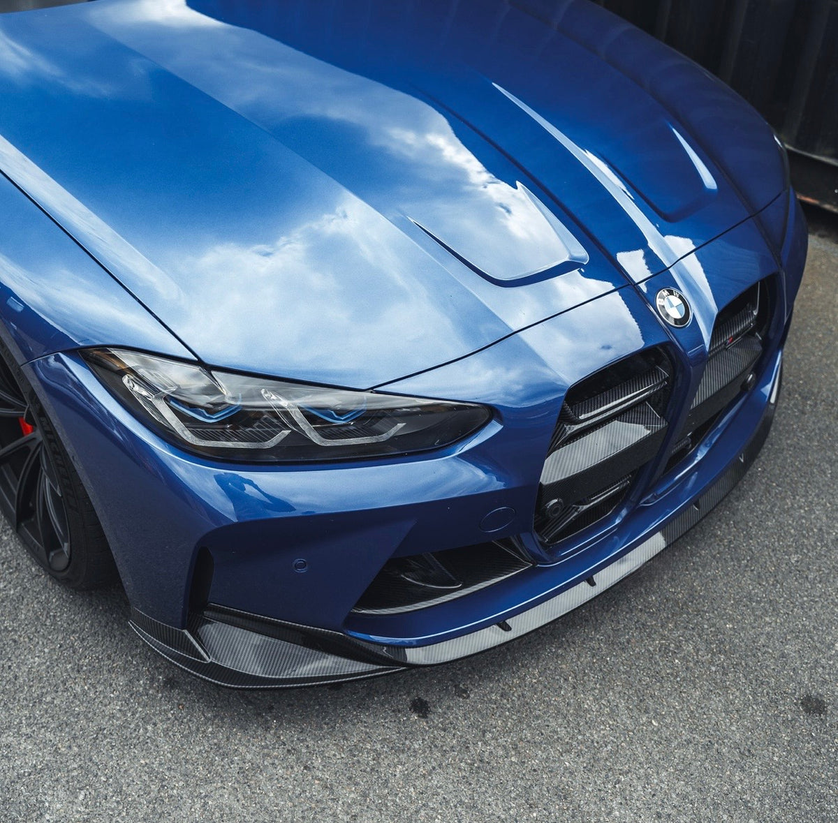 Detailansicht der V7 Dry-Carbon Frontlippe an der Frontstoßstange eines blauen BMW M3 G80