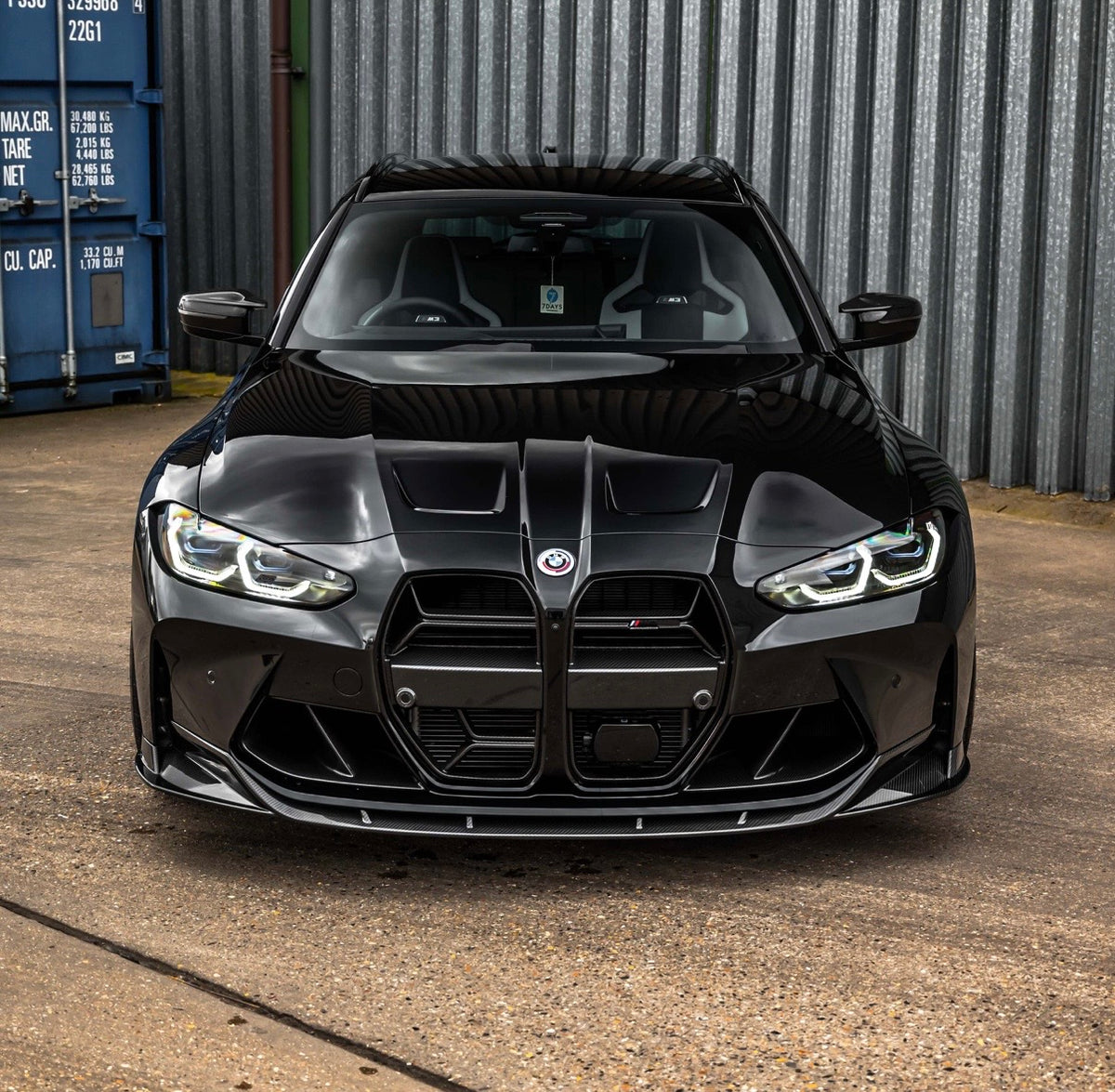 Schwarzer BMW M3 G80 mit montierter V7 Dry-Carbon Frontlippe in der Vorderansicht