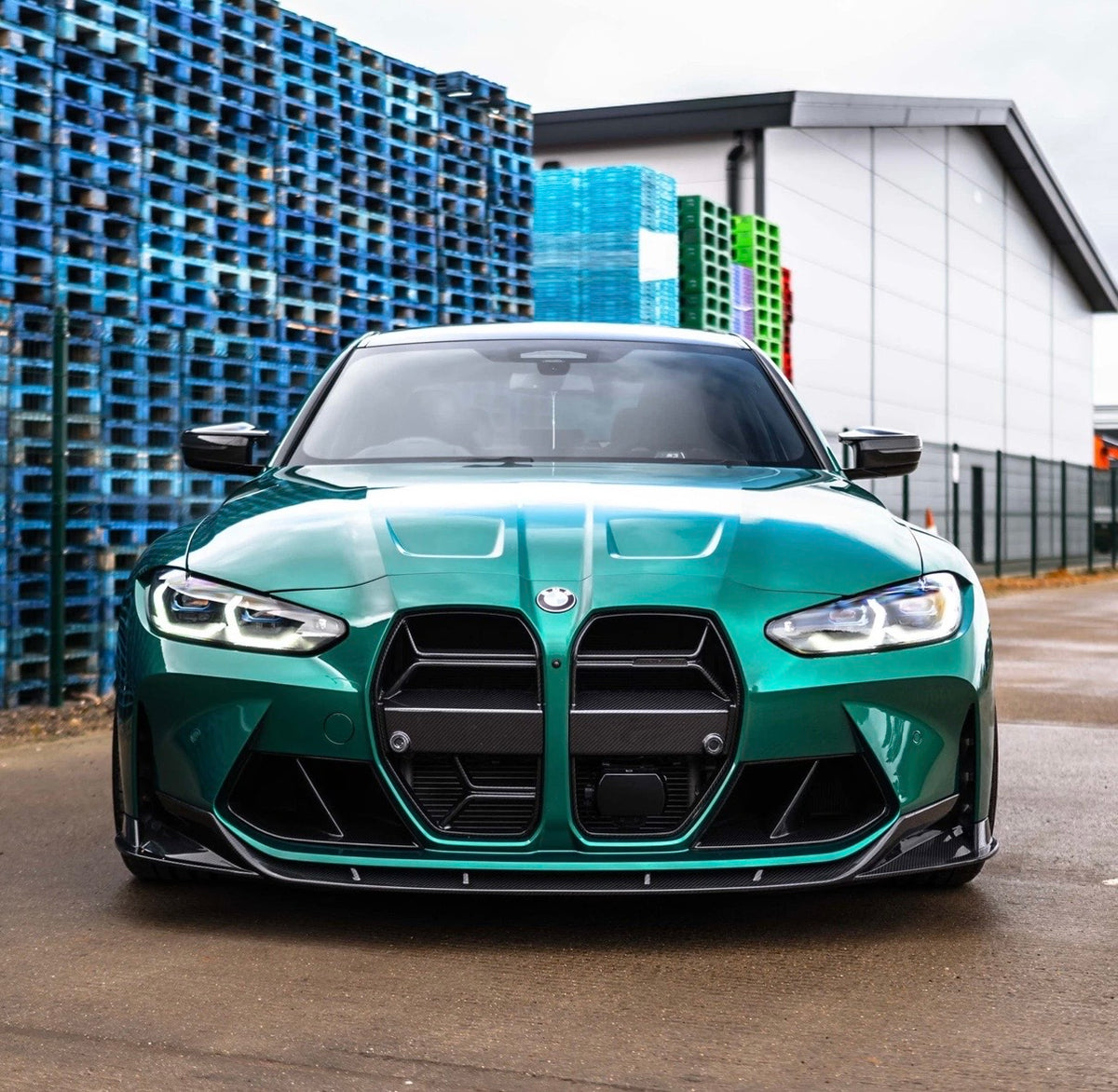 Türkisgrüner BMW M3 G80 mit V7 Dry-Carbon Frontspoiler in der direkten Frontansicht