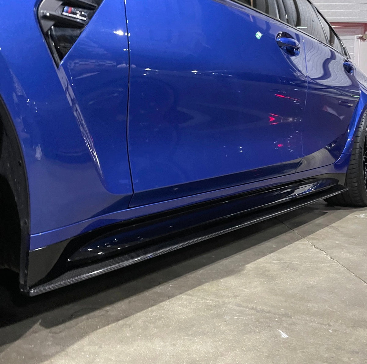 Nahaufnahme der CPG+ V7 Carbon Seitenschwelleransätze am blauen BMW M3 G80