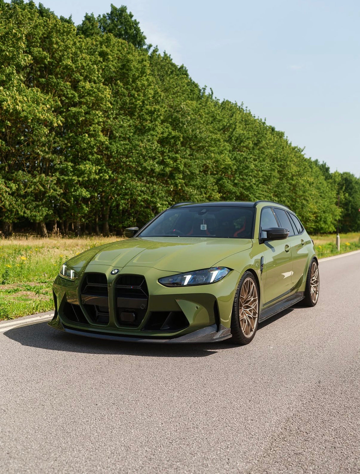 Grüner BMW M3 G80 mit CPG+ V8 Dry-Carbon Frontlippe in der schrägen Frontansicht
