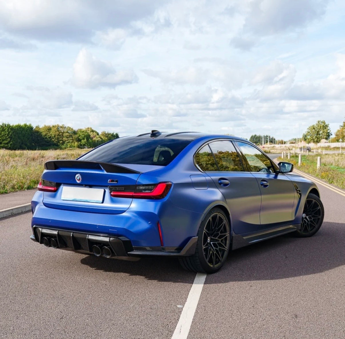Blauer BMW M3 G80 mit V8 Carbon Heckspoiler aus seitlicher Heckperspektive