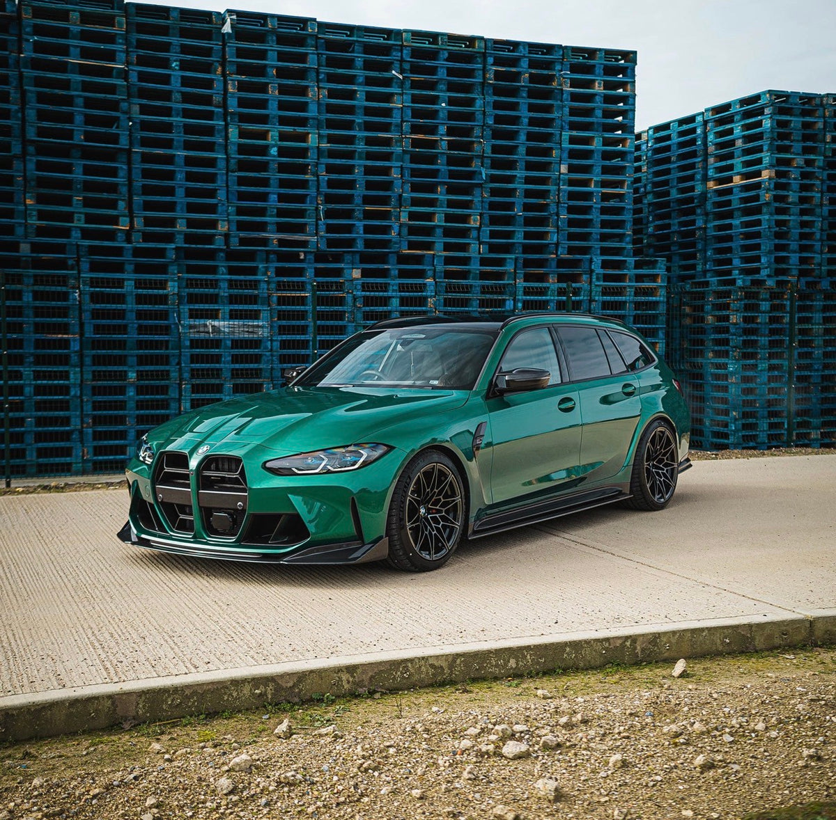 Grüner BMW M3 G80 mit V9 Carbon Frontspoiler in der schrägen Fahrzeugansicht