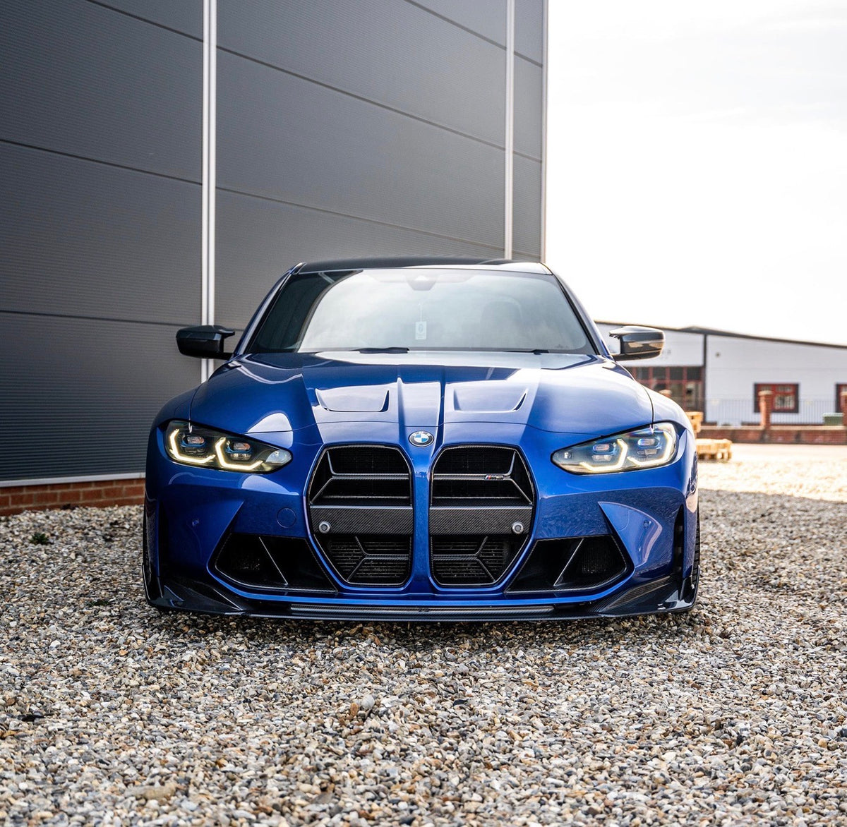 Blauer BMW M3 G80 mit montierter CPG+ V9 Dry-Carbon Frontlippe in der direkten Vorderansicht
