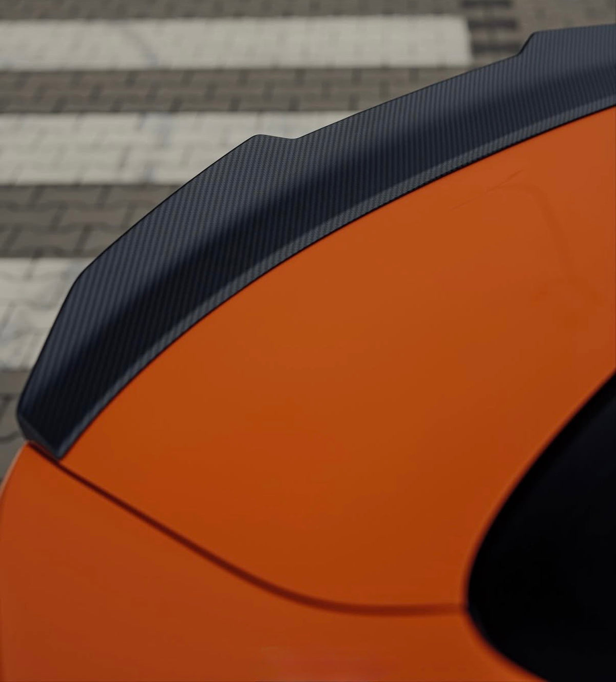 CPG+ V2 Carbon Heckspoiler am orangefarbenen BMW M4 G82 – Detailansicht der seitlichen Spoilerkante
