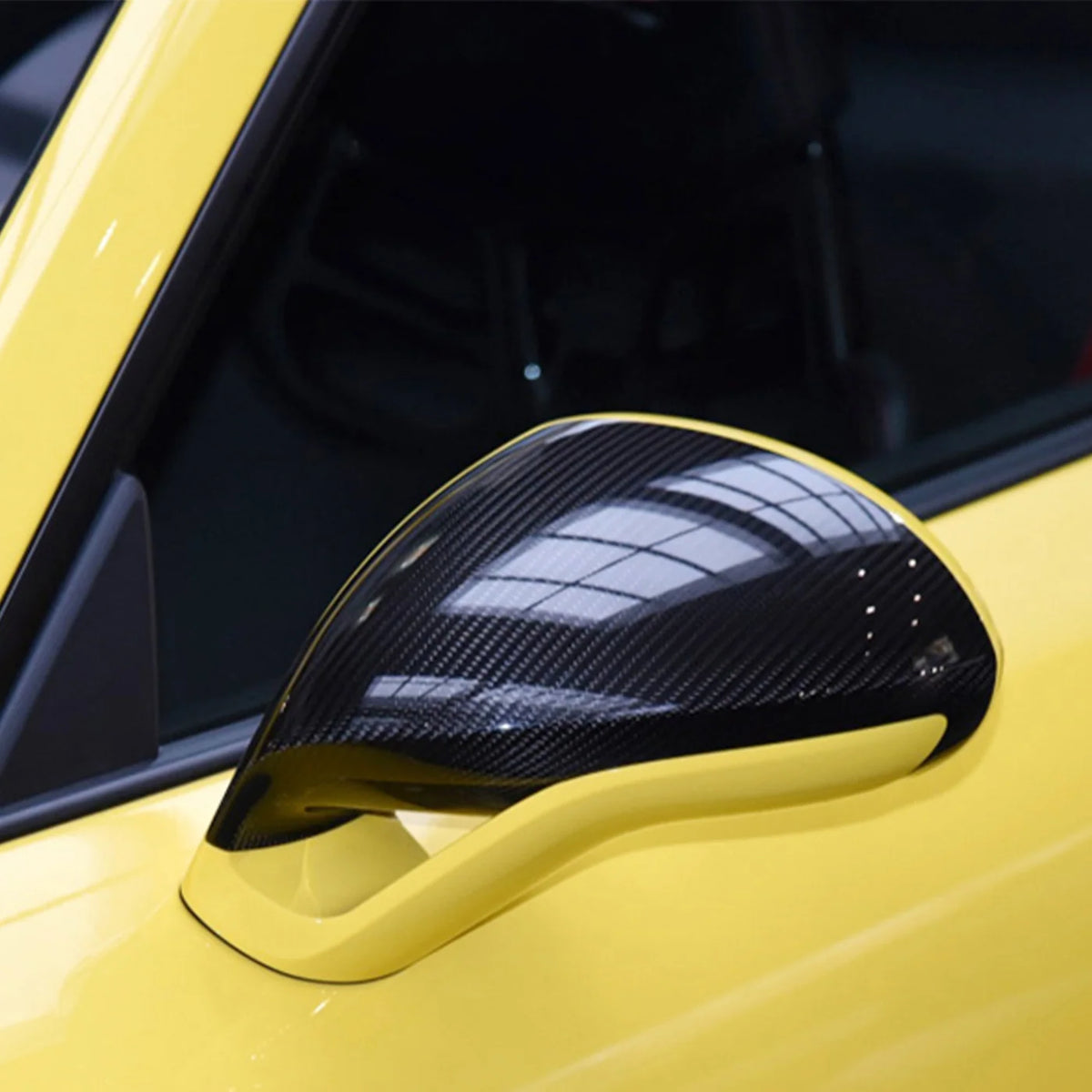 Dry-Carbon Spiegelkappe an einem gelben Porsche – Nahaufnahme der montierten Spiegelkappe mit glänzender Carbonfaserstruktur